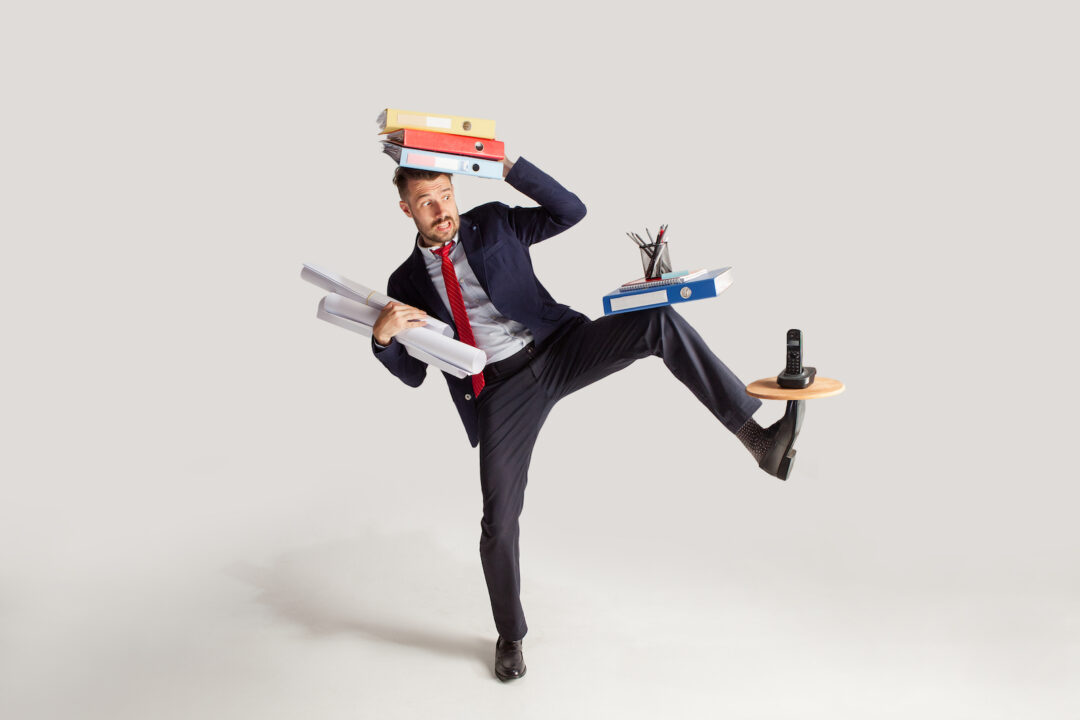 photo-young-businessman-in-a-suit-juggling-with-office-supplies-in-his-office-isolated-on-white